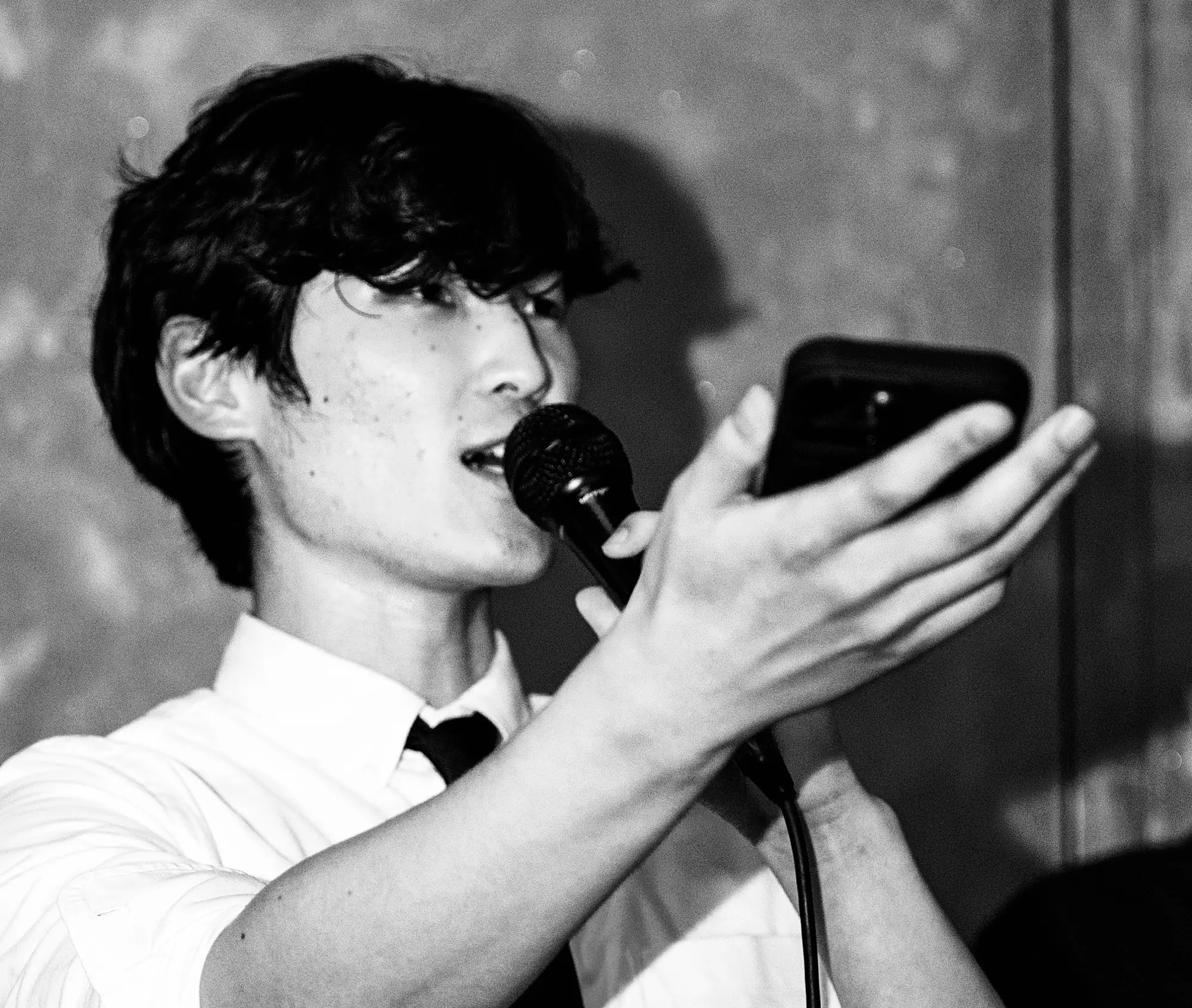 Young Park speaking into a microphone while reading from his phone.