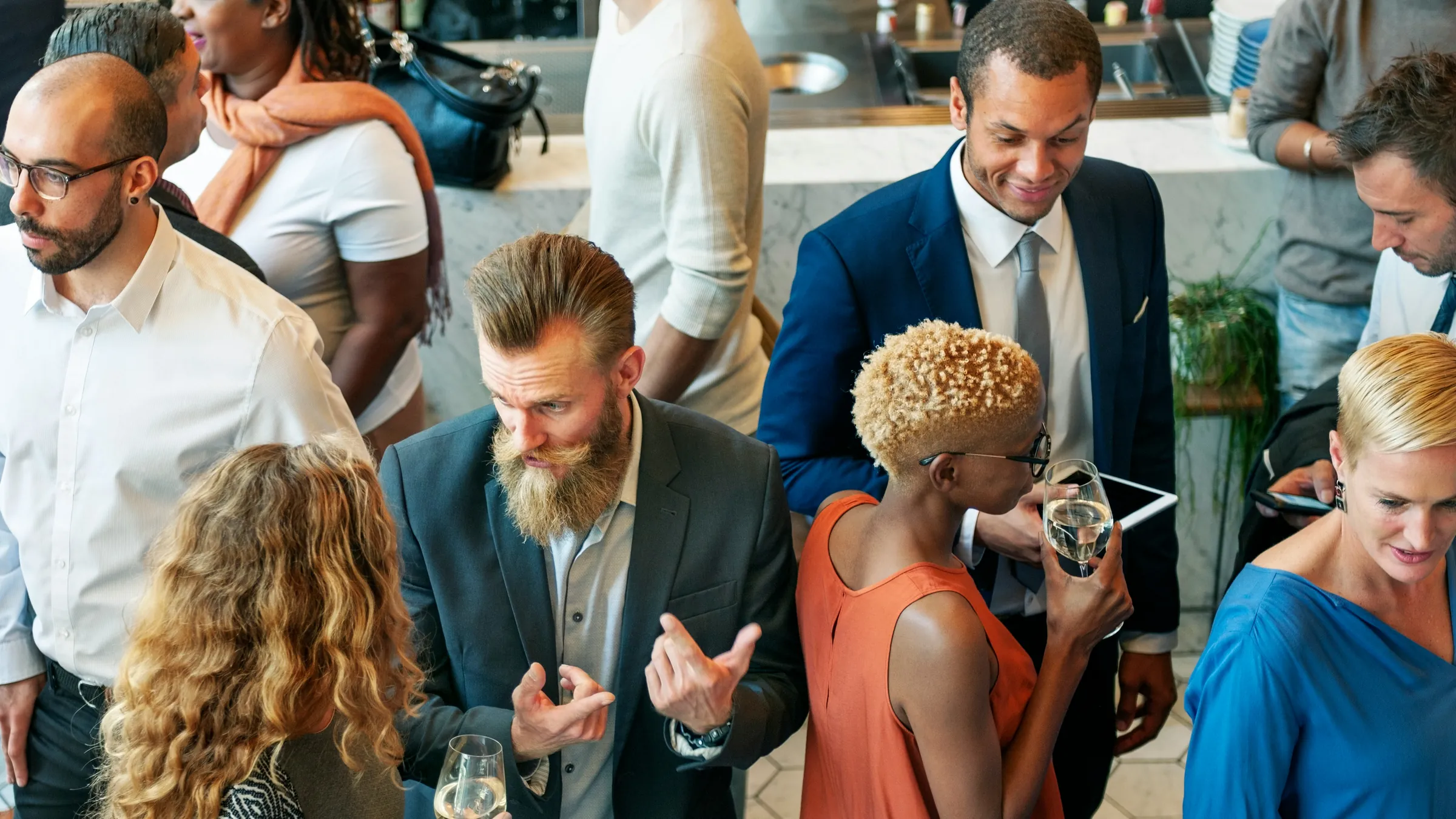Professionals talking over drinks at a crowded in-person networking event.