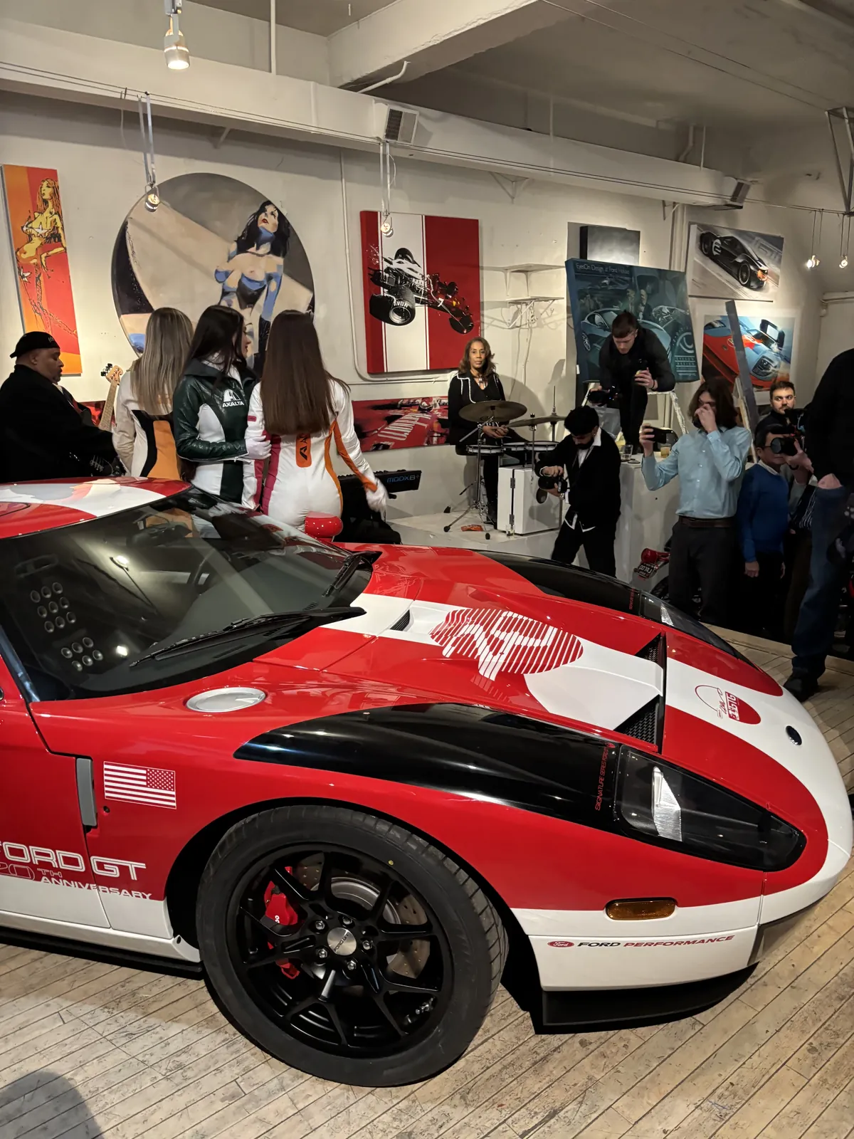 Guests gathered around a red and white Ford GT inside a Detroit art gallery during a networking event.