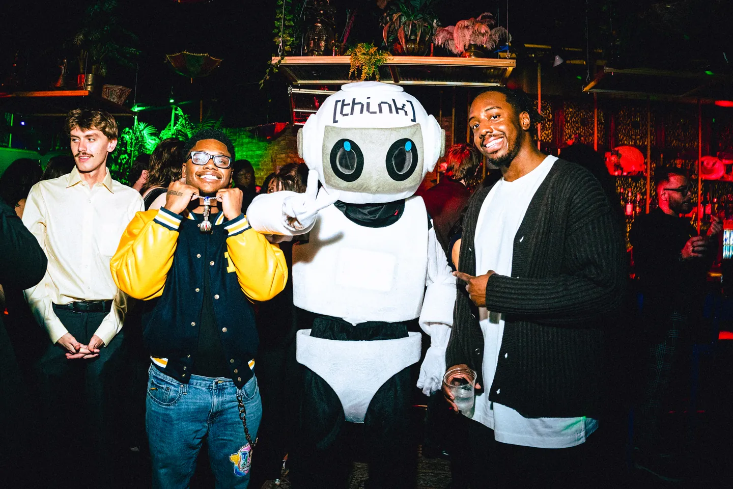 Guests at THE BACK ROOM Vol. 1 posing with the Think Technologies robot mascot.