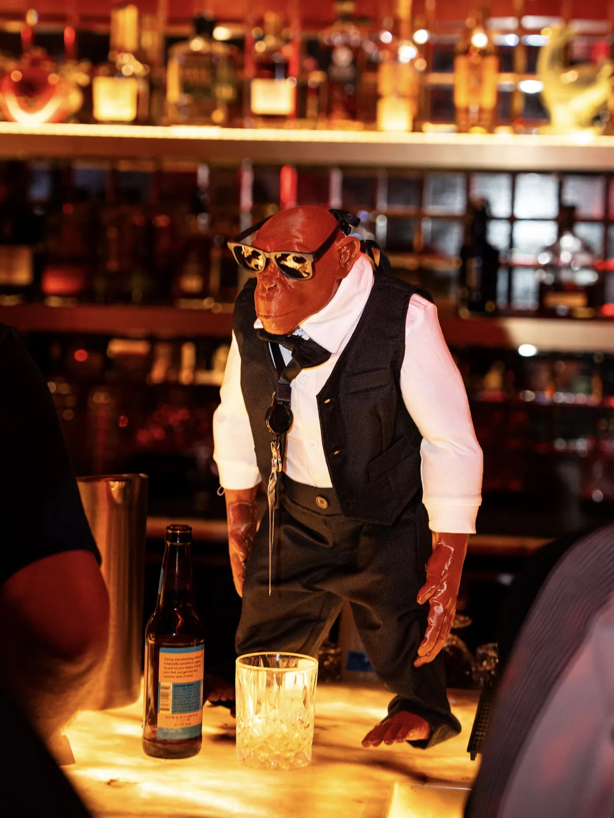 A chimpanzee sculpture in sunglasses, vest, and bow tie standing on the bar at THE BACK ROOM Vol. 2.