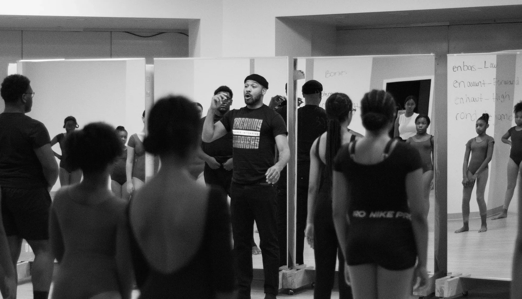 An instructor leads a class of young dancers in a mirrored DWDA studio.